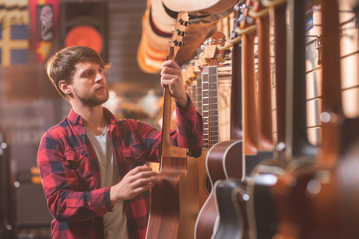 A young musician choosing a guitar in a music store