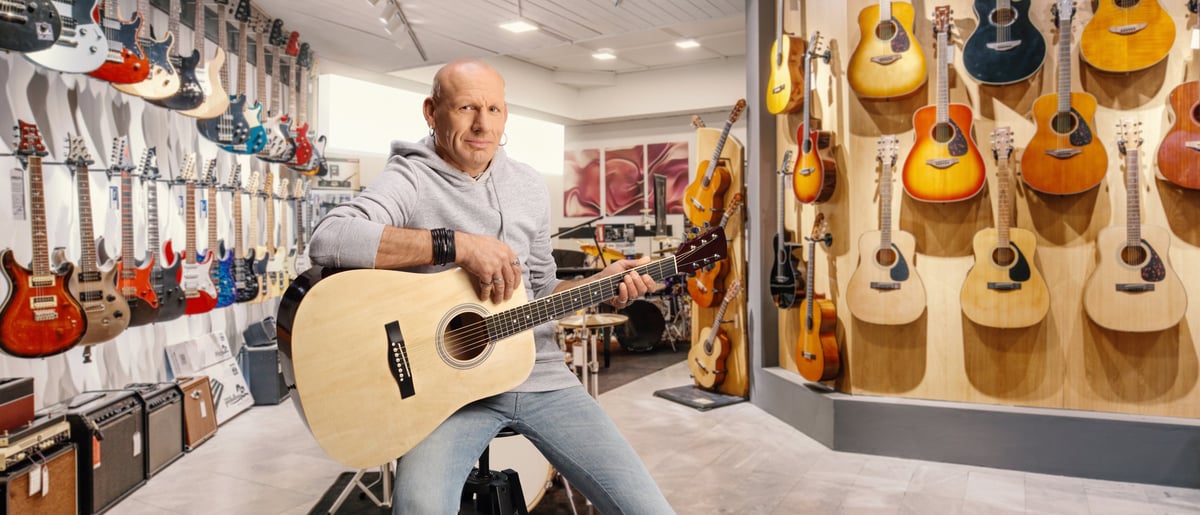 A musician with an acoustic guitar sitting in a music store