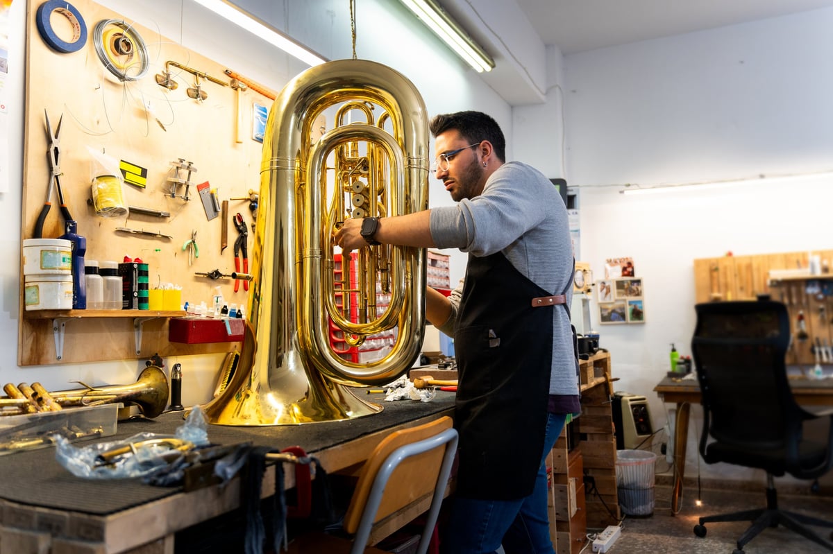 An instrument repair technician examining and repairing an instrument in a workshop
