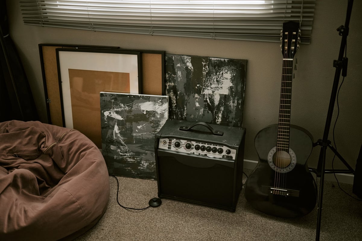 Acoustic guitar standing beside an audio amplifier in a home studio setting